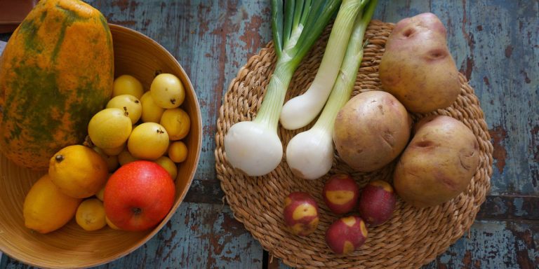 Fresh potatoes, onions, fruit arranged in woven baskets